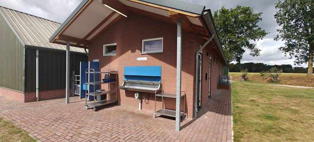 Bakstenen sanitairgebouw van Camping Lindershoeve met een overdekte afwasplek en meerdere spoelbakken